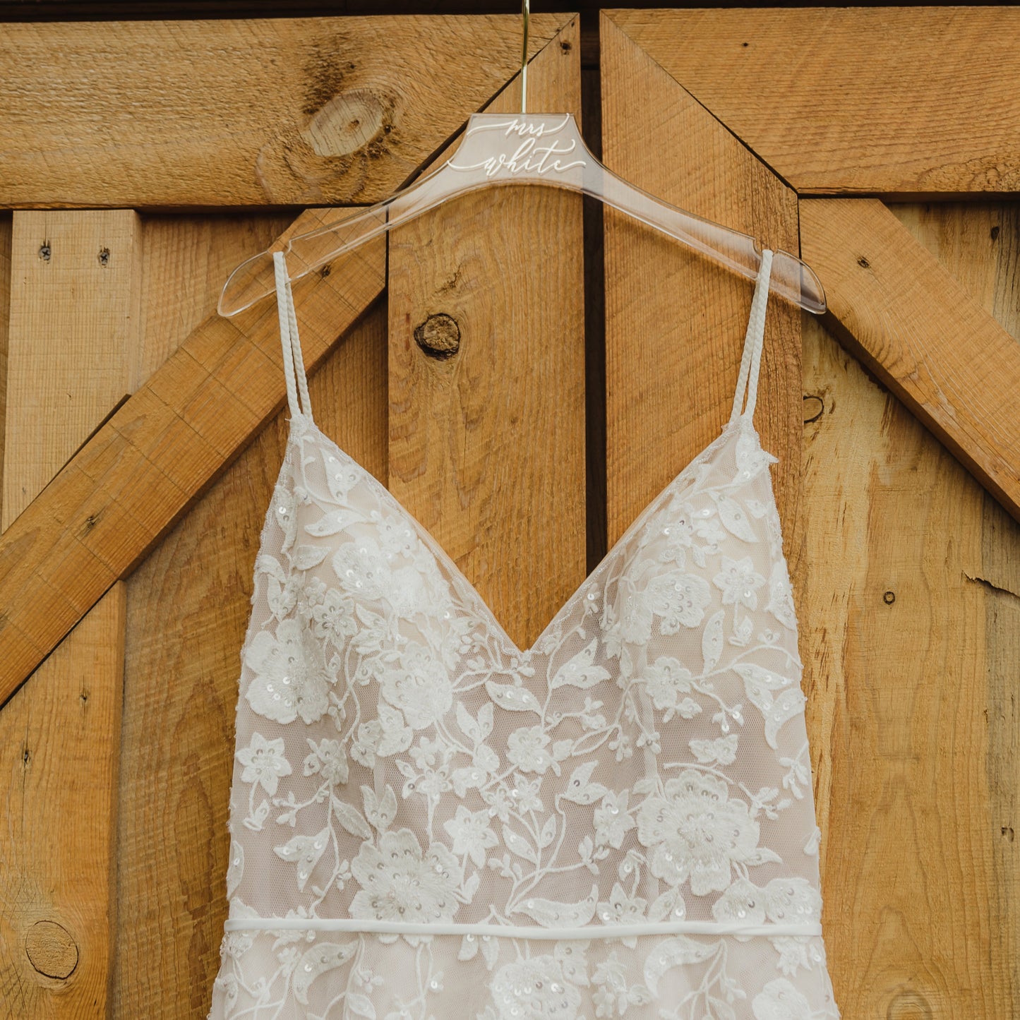 Close-up image of a clear acrylic wedding dress hanger with the name 'mrs white' in gold cursive font.