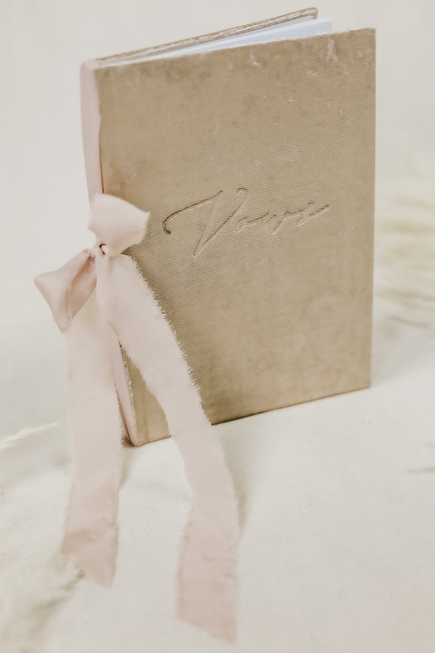 Handmade vow book, featuring a velvet cover in white, silver, or champagne, with 'vows' embossed and a ribbon tie detail