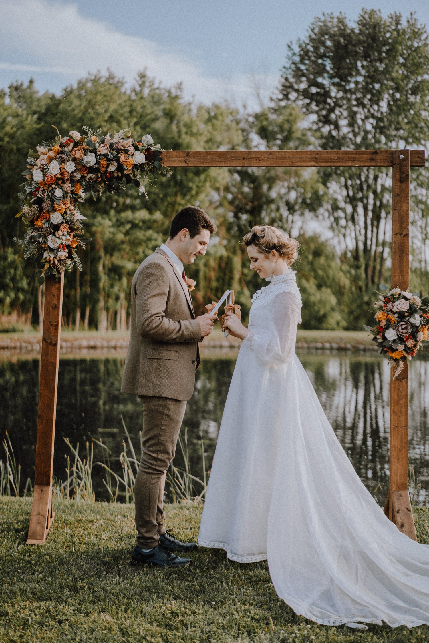 Couple Exchanging Vows with Velvet Vow Books Tied with Silk Ribbon at Wedding Ceremony