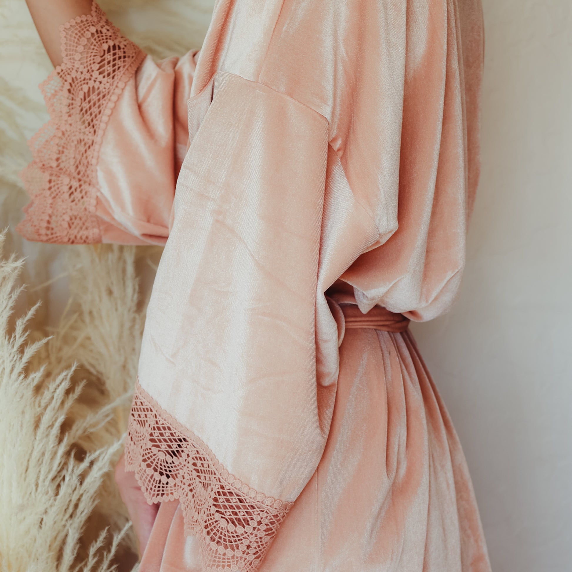 Image of a blush pink velvet robe with lace sleeve details, designed for bridesmaids